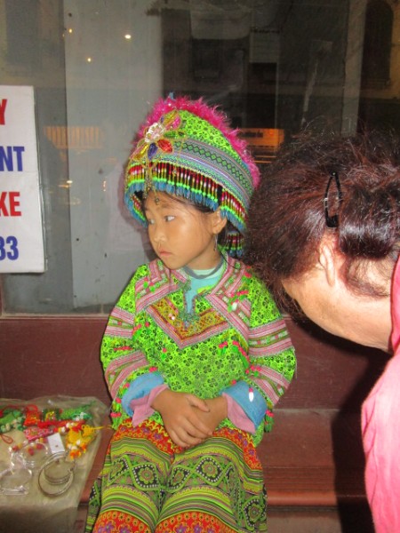 夜8時ごろ、気温が下がり寒さに震えながら民族衣装でみやげ物を売っている幼い女の子。